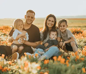 Family of five sitting together in a sunlit field
