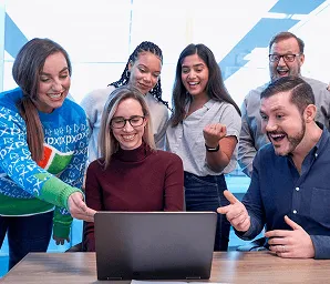 Diverse group gathered around a laptop and coordinating together